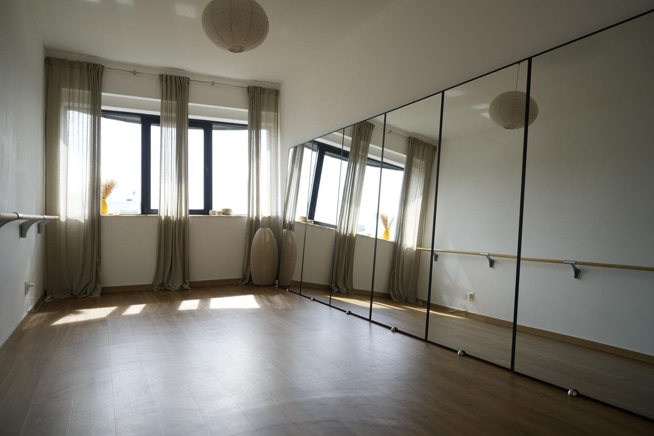 Interior of MokoBoko boutique fitness studio featuring large windows, wall-to-wall mirrors, and a neutral aesthetic, optimized for Mat Pilates and barre training.