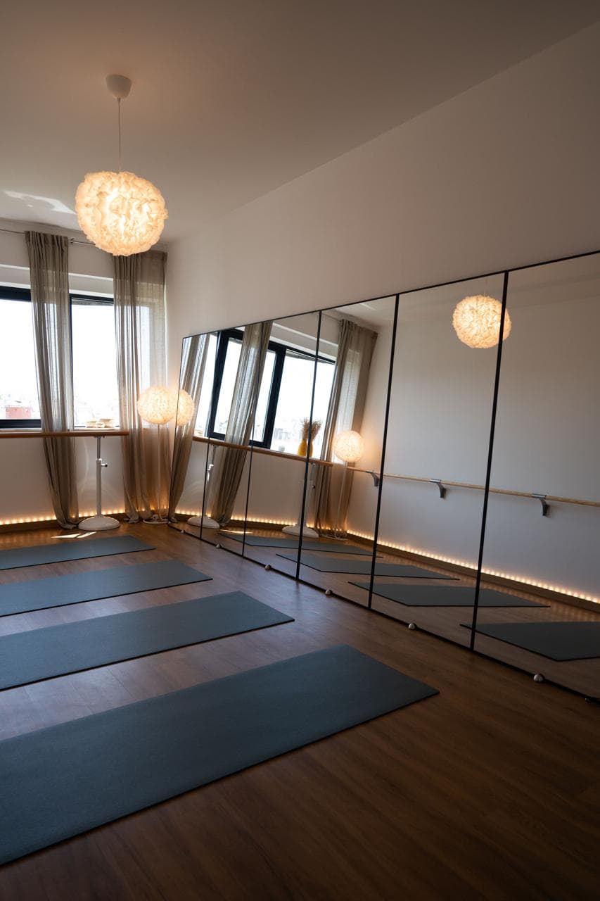 View of the clean, minimalist workout space at MokoBoko featuring floor mats, mirrors, and barre equipment.