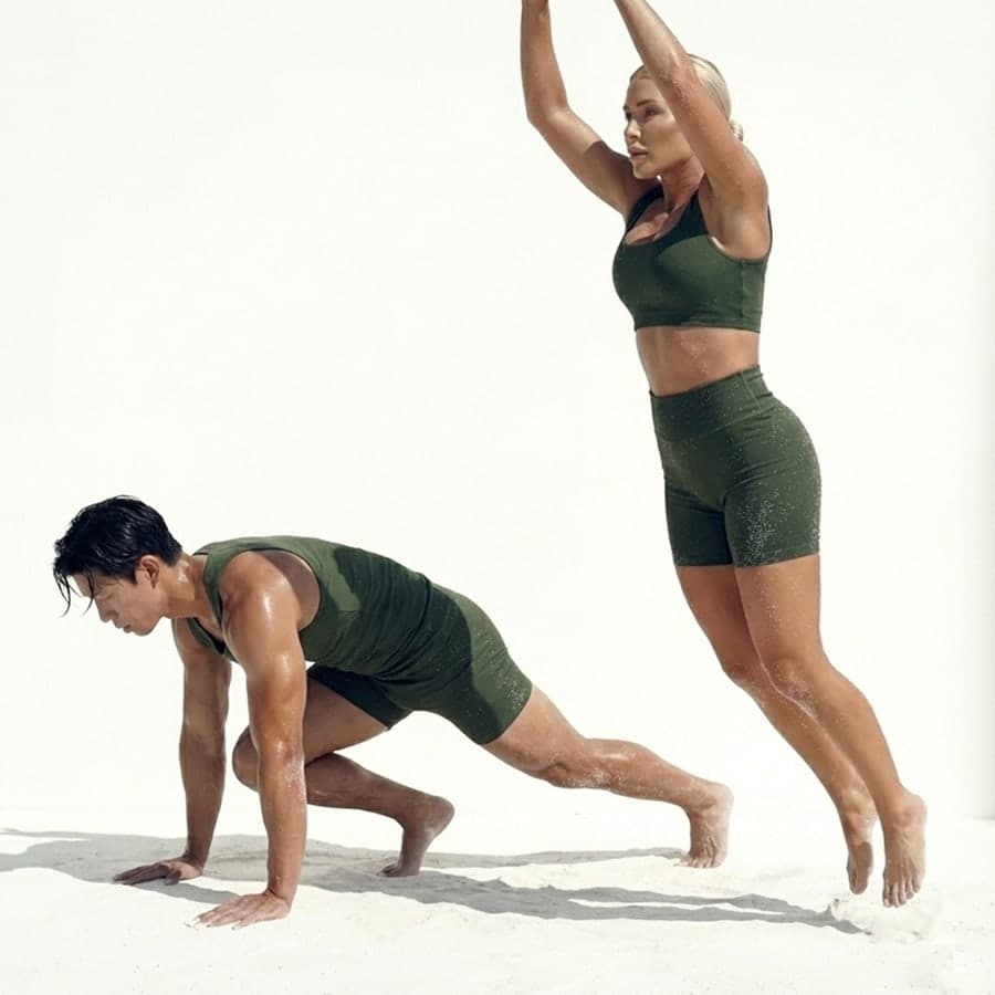 Man and woman in olive green sets doing explosive HIIT jumps and planks for year-round consistency in Lisbon