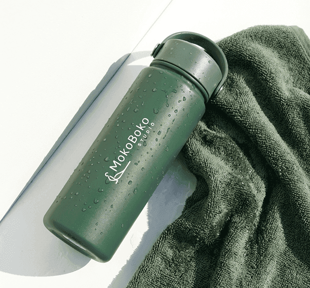 Green MokoBoko water bottle resting on a green towel